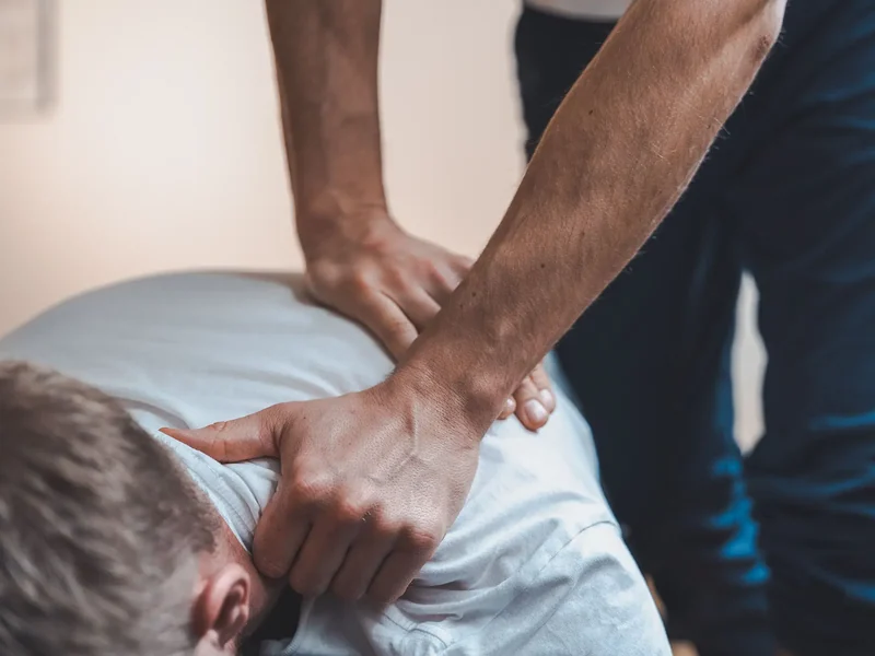 Physical therapist assessing a patient's neck and back movement and mobility